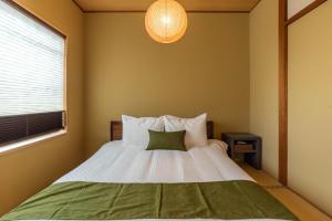 sypialnia z łóżkiem z białą pościelą i zieloną poduszką w obiekcie Bijou Suites Pieces w Osace