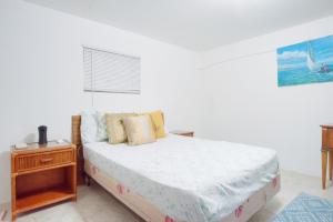 een witte slaapkamer met een bed en een nachtkastje bij Hillcrest in Nassau