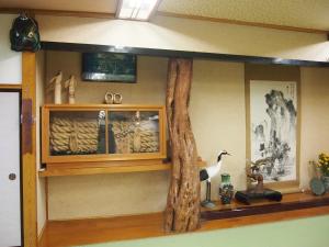 ein Zimmer mit einem Regal mit einem Fake-Baum in der Unterkunft Hagurokan in Tsuruoka
