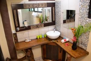 a bathroom with a sink and a mirror at Haere Mai I Te Fare in Teavaro