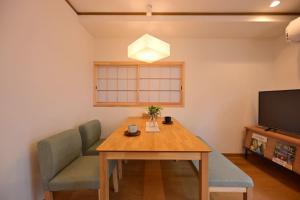 a dining room with a table and chairs and a television at OMM STAY in Tokyo
