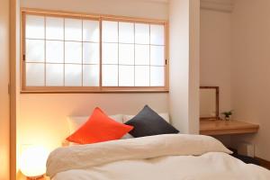 a bed with colorful pillows sitting under a window at OMM STAY in Tokyo