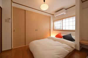 a bedroom with a white bed with a red pillow at OMM STAY in Tokyo