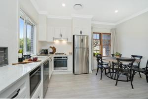 a kitchen with a table and a stainless steel refrigerator at Accommodation Hunter - Adams Street Maitland in Maitland