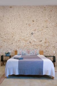 ein Schlafzimmer mit einem Bett mit einer Steinmauer in der Unterkunft Casa Dell´acqua Merida in Mérida