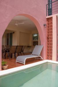 ein rosafarbenes Haus mit einem Pool und einem Stuhl in der Unterkunft Casa Dell´acqua Merida in Mérida