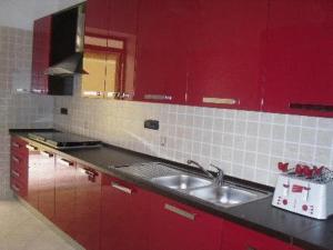 a red kitchen with a sink and red cabinets at B&B Mediterraneo in Torre Melissa