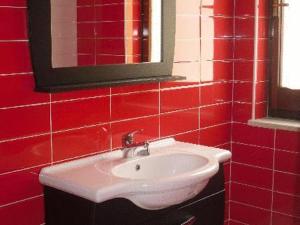 a red tiled bathroom with a sink and a mirror at B&B Mediterraneo in Torre Melissa