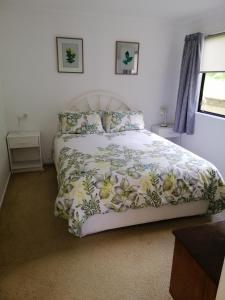 1 dormitorio con 1 cama con colcha de flores en SilverSands, en Waihi Beach