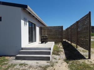 a house with a fence and a bench on the porch at Nirvana in Struisbaai