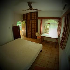 a bedroom with a bed and a desk and a window at New Creation Guest House in Auroville