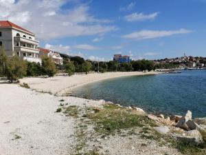 a beach next to the water with a building at Apartman Gilan in Seget Vranjica