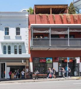 un gruppo di persone seduti su una panchina di fronte a un edificio di 1 Private King Single Bed In Sydney CBD Near Train UTS DarlingHar&ICC&C hinatown - ROOM ONLY a Sydney