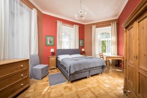 プラハにあるリリオヴァ アパートメンツの赤い壁のベッドルーム1室、ベッド1台、デスクが備わります。
