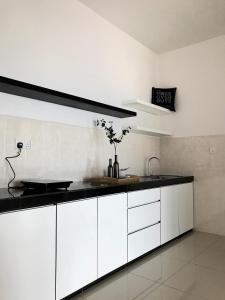 a kitchen with white cabinets and a black counter top at Boulevard Service Apartment KL by Airhost in Kuala Lumpur