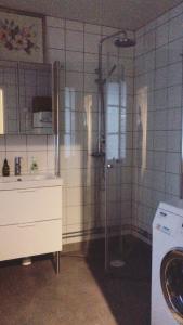 een badkamer met een douche, een wastafel en een wasmachine bij Pensionatet in Piteå