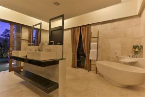 a bathroom with a tub and two sinks and a large mirror at Villa Kumuda by Nakula in Canggu