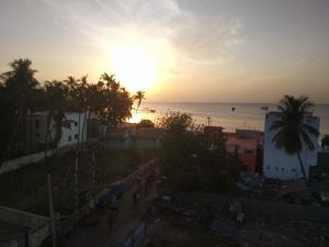 Hotel SAARA في رامسوارام: غروب الشمس على المحيط مع أشجار النخيل والمباني