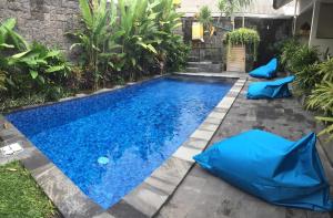 a swimming pool in a backyard with blue umbrellas at Jukung Dua Guest House in Sanur
