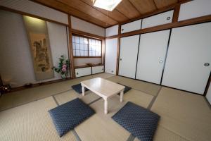 een lege kamer met een tafel en een aantal ramen bij Taro's House Kamakura Hase in Kamakura