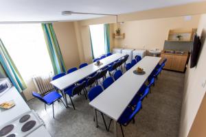 een conferentieruimte met witte tafels en blauwe stoelen bij PD Hostel in Dunaújváros