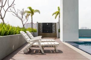 two white lounge chairs sitting next to a swimming pool at Boulevard Service Apartment KL by Airhost in Kuala Lumpur