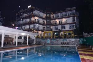 a hotel with a swimming pool in front of a building at Highland Village Resort in Dharmsāla