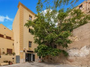 voor een gebouw staat een boom bij Martini Rooms Castello in Cagliari