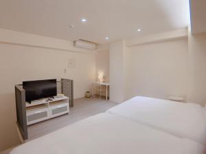 a white bedroom with a bed and a tv at In Fengchia in Taichung
