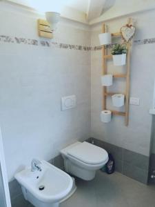 La salle de bains est pourvue de toilettes blanches et d'un lavabo. dans l'établissement Appartamento Olea, à Arco