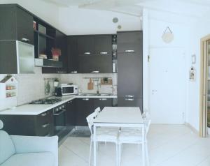 アルコにあるAppartamento Oleaのキッチン(黒いキャビネット、白いテーブルと椅子付)