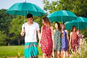 a group of people walking down a field holding umbrellas at Amuna Ayurvedic Retreat in Sigiriya