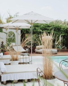 un patio con ombrellone, sedie e piscina di Villa Paradiso Charme&Design ad Arquata Scrivia