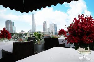 a table with a vase of red flowers on a balcony at Anpha Boutique Hotel in Ho Chi Minh City