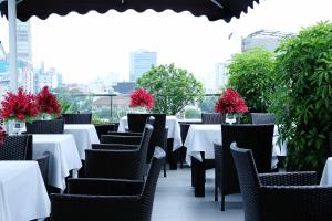 a restaurant with white tables and chairs and red flowers at Anpha Boutique Hotel in Ho Chi Minh City
