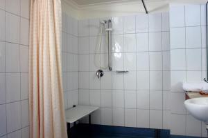 a white tiled bathroom with a shower and a sink at Kobbers Motor Inn in Dalby