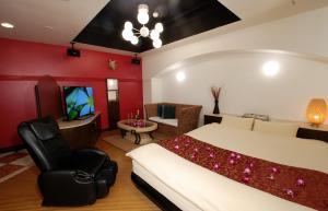 a bedroom with a bed and a chair and a television at Comfort Hotel Hu in Koshigaya