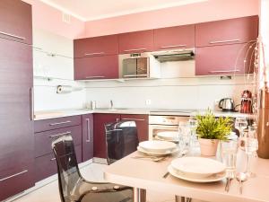 uma cozinha com armários roxos, uma mesa e cadeiras em VacationClub – Osiedle Podgórze 1C Apartament 22 em Szklarska Poręba