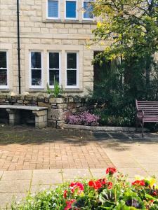 un banco de parque frente a un edificio con flores en 3 Argyle Place en Dornoch