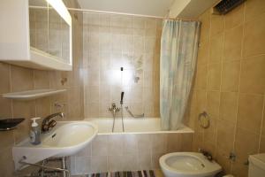 a bathroom with a tub and a sink and a toilet at Apartment Victoria in Crans-Montana