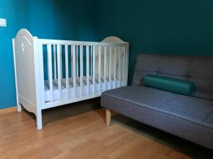 - un lit bébé et un canapé dans l'établissement La Ferme des Roses, à Tournai