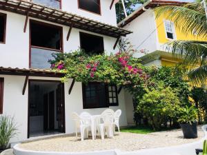 a table and chairs in front of a house with flowers at Casas Coloniais in Morro de São Paulo