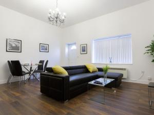 a living room with a black couch and a table at Live in Leeds Greenhill Bungalows in Leeds