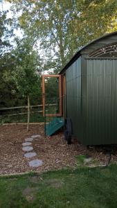 a green shed with a door in a yard at Glamping Malvern shepherd hut in Malvern Link