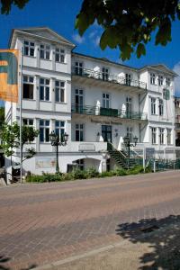 a white building on a street next to a road at Pension Haus Pommern in Ahlbeck