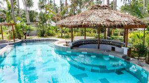 a swimming pool with a straw umbrella and a swimming pool at Nacpan Beach Glamping Managed by H Hospitality Group in El Nido