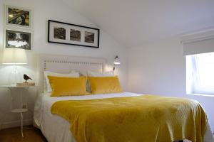 ein Schlafzimmer mit einem Bett mit gelben Laken und einem Fenster in der Unterkunft Typical Village Oporto 24 in Porto