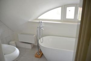 a white bathroom with a tub and a window at Deichkind - Reetdachhaus direkt am Elbdeich in Mödlich
