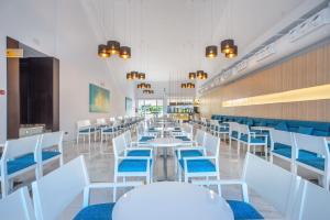 uma sala de jantar com mesas brancas e cadeiras azuis em Globales Playa Estepona em Estepona