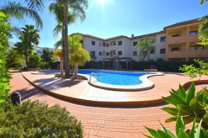 a pool in a courtyard with palm trees and a building at Apartamento Benvinguts I in Jávea